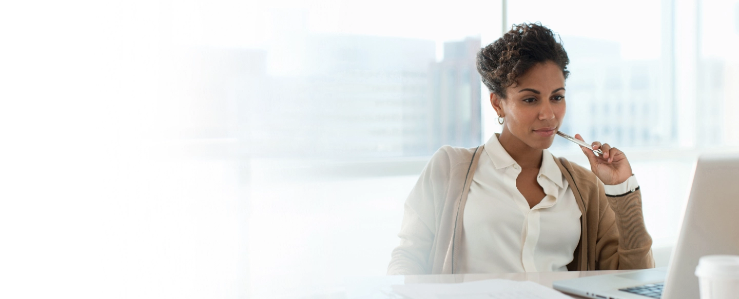 Kvinna i vit blus framför laptop