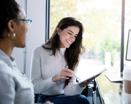 Två glada, kvinnliga ingenjörer diskuterar CV-tips